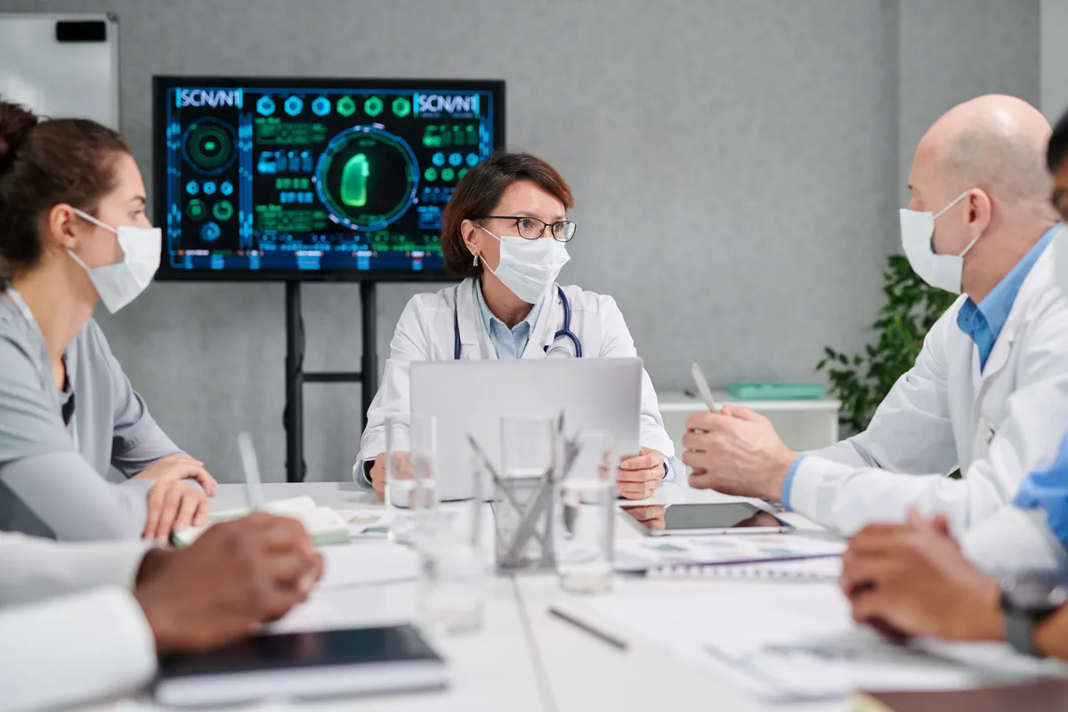 Medical team meeting around a conference table to review patient monitoring data